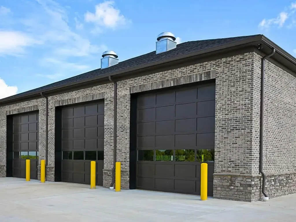 Row of dark commercial overhead garage doors on a brick building