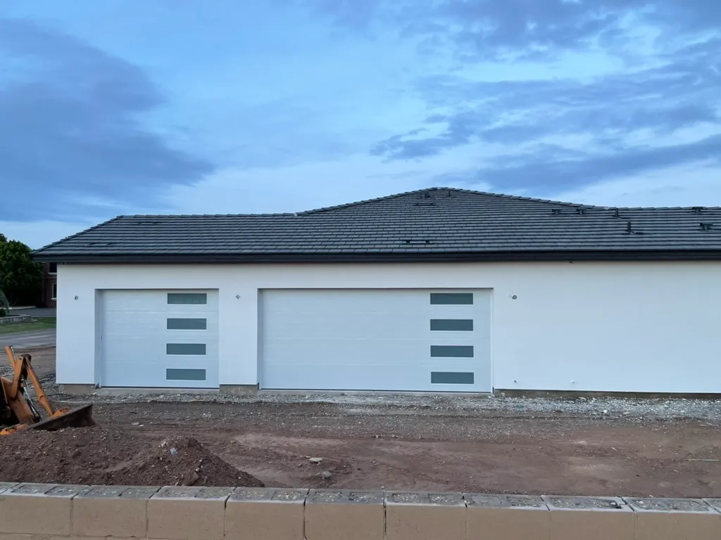 New white garage doors with window inserts on a new-build home