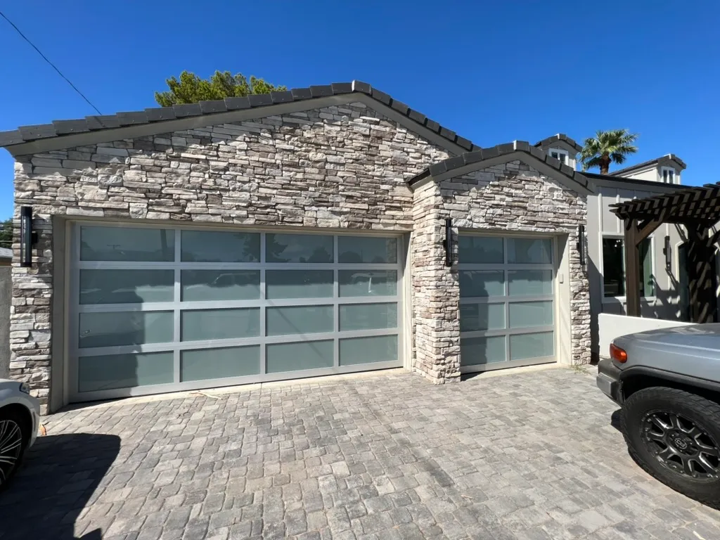 Glass garage door installed in a stacked stone wall in Phoenix